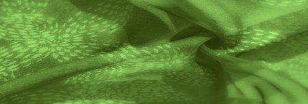 Blur effect over green fabric with soft folds and natural motifs creates a serene, calming backdrop. The subtle leaf-like patterns add organic interest to the textile surface.の写真素材