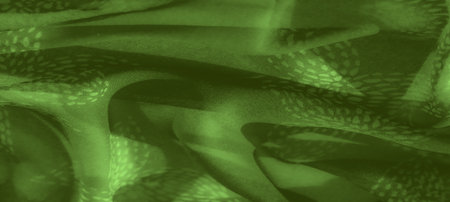 Blurred image of green fabric with intricate patterns, forming a layered, textured surface. Soft folds add depth and dimension to the abstract, nature-inspired design.の写真素材