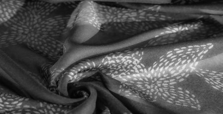 Blurred grayscale fabric with delicate white patterns swirling across soft folds, creating a sense of luxury. Gentle shadows and highlights accentuate the fabric's sophisticated texture.の写真素材