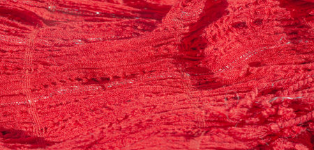 Blur of richly textured red fabric intricately woven with subtle silver threads, creating a captivating interplay of light and shadow across its soft, plush surfaceの写真素材