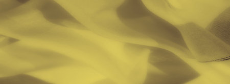 Blur of yellow fabric in soft, layered folds, exuding warmth and a smooth, gentle texture, perfect...