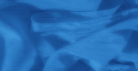 Blurred image of blue fabric with soft shadows and light folds, offering a smooth and serene visual appeal. Its simplicity makes it a versatile choice for various artistic needs.の写真素材