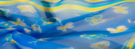 Blurred floral details in yellow and white decorate the flowing blue fabric, creating a lightweight and airy aesthetic with a bright and cheerful vibe.の写真素材
