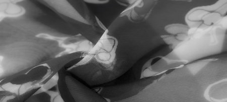 Blurred image highlighting the artistic beauty of floral motifs on flowing monochrome fabric. The...