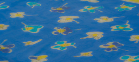 Blur effect enhances the sheer blue fabric with overlapping floral patterns in vibrant yellow and soft white. The lightweight material captures light beautifullyの写真素材