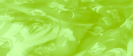Blur of bright green sheer fabric adorned with elegant floral patterns and smooth, reflective folds, creating a dynamic yet soft appearance for creative visuals.の写真素材