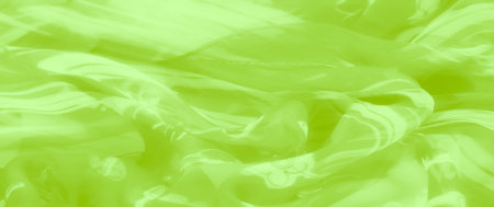 Blur of lime green fabric with smooth folds and a glossy finish, detailed with intricate floral and abstract patterns for a dynamic, vibrant look.の写真素材