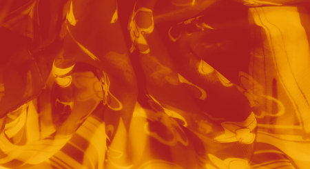 Blur of a vivid orange fabric with floral outlines and striped accents, flowing gracefully with warm...
