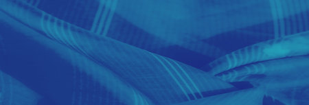 Blurred folds of blue fabric with soft floral patterns and subtle stripes, creating a soothing and...