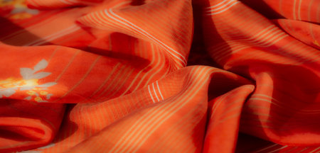 Blur of a vibrant orange fabric with fine white stripes and delicate floral patterns, showing a soft...