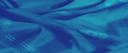 Blur effect on vibrant blue fabric showing soft folds with subtle floral patterns and striped...
