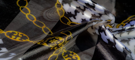 Blur of glossy black and white textile with intricate golden chain motifs. The luxurious folds and...