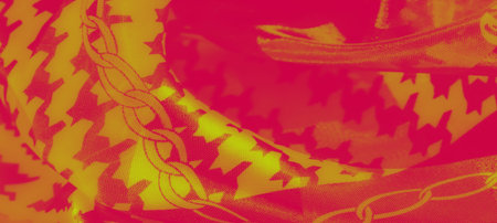 Blur of detailed fabric in bold yellow and red tones with floral and chain designs, creating a rich,...