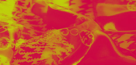 Blur. A vibrant abstract image showing intricate yellow and red fabric patterns with swirling floral...