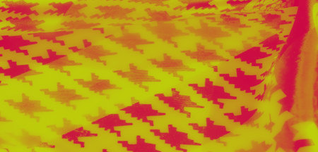 Blur. A captivating close-up of patterned fabric with yellow and red tones, featuring floral motifs,...