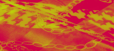 Blur of bold red and yellow fabric with intricate chain patterns and angular designs. The vibrant...