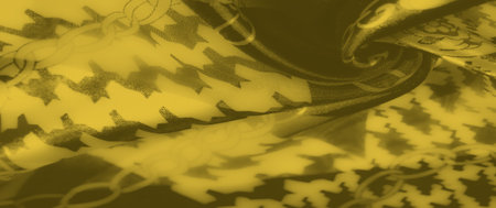 Blur of soft yellow fabric with intertwining chain and geometric patterns. A dynamic flow of folds...
