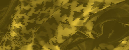 Blurred folded yellow fabric with decorative chain motifs and bold geometric shapes, offering a...