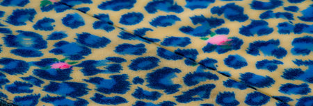Blurred view of blue leopard-like patterned fabric with pink floral details layered on a beige...