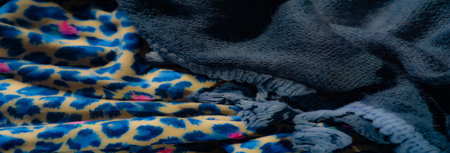 Blur: A mix of textured dark gray fabric with braided details layered with a vivid blue and beige animal-inspired patterned fabric for a striking combination of textures.の写真素材