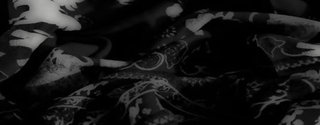 Blurred grayscale fabric featuring swirling folds and exotic animal patterns, combining intricate...