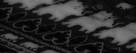 Blur of grayscale fabric with layered folds and abstract patterns featuring animal motifs. The interplay of shadow and light creates a striking visual effect.の写真素材