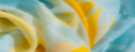 Blurred close-up of yellow and blue fabric, with smooth folds and an elegant interplay of textures and colors, offering a captivating abstract composition.の写真素材