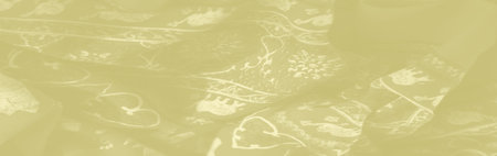 Blur: A soft, golden fabric with intricate patterns of elephants and floral motifs, gently folded to showcase its elegant and luxurious texture.の写真素材