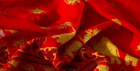 Blur emphasizes the bold red fabric featuring golden elephant motifs and heart-shaped patterns, evoking a sense of traditional elegance and festive celebration.の写真素材