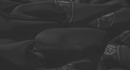 Blur reveals ornamental floral motifs and braided fringes on dark fabric with a shimmering geometric border, showing intricate craftsmanship and elegance.の写真素材