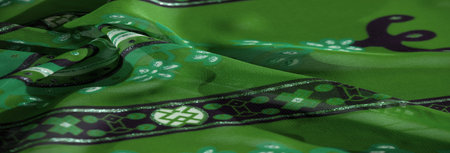 Blur: An artistic green fabric with dynamic abstract and floral patterns, featuring vivid black and...