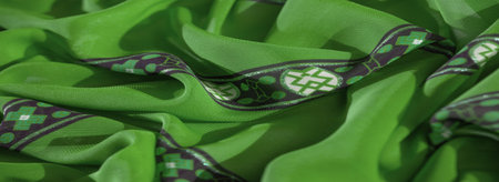 Blur of elegant green fabric with purple and white decorative patterns. The intricate details and...