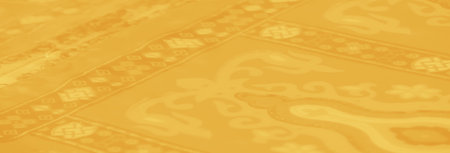 Blurred focus on yellow fabric with symmetrical floral and geometric patterns, highlighted by glitter accents and soft folds, exuding an aura of sophistication.の写真素材