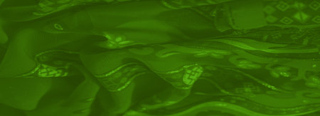 Blurred view of flowing green fabric with intricate patterns and a glittering sheen, creating a vibrant and textured appearance.の写真素材