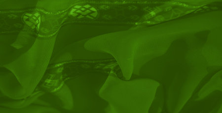 Blur of soft green fabric with overlapping folds and intricate motifs, accented by subtle shimmer for a refined and decorative aesthetic.の写真素材