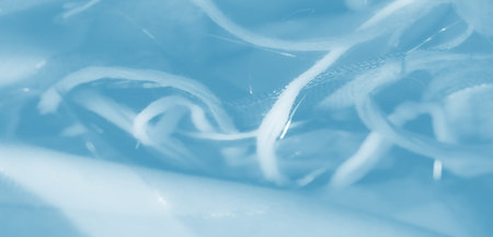 Blurred intricate weaves of light blue fabric create a delicate and flowing texture. The soft fabric forms gentle folds with a dreamy, translucent effect.の写真素材
