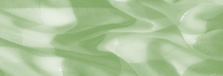 Blurred artistic view of green fabric with intertwined threads and layered textures, creating a dynamic visual with a soft, glowing appearance and abstract beauty.の写真素材