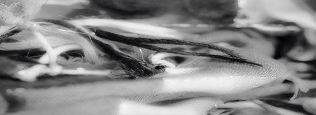 Blurred grayscale fabric close-up with layered folds, showing the interplay of texture and soft patterns. The subtle weave adds an elegant, flowing appearance.の写真素材