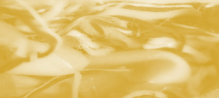 Blurred layers of yellow fabric with soft mesh textures and flowing waves, creating a radiant...