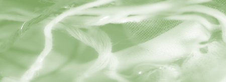 Blurred image of green fabric with loose fibers and smooth folds, showcasing a delicate interplay of textures and light for an abstract, artistic effect.の写真素材