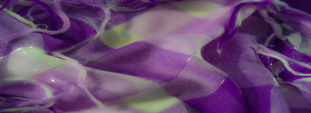 Blurred focus on shimmering purple and white fabric with layered textures and loose threads. The interplay of light and shadow highlights the fabric's intricate details.の写真素材