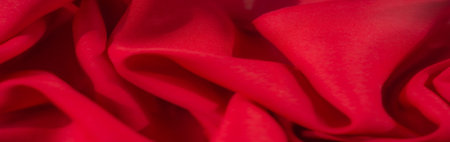 Blur of vibrant red fabric with a smooth texture and soft folds, creating a dynamic and elegant...