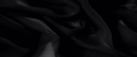 Blur, black fabric captured in a flowing motion, showcasing soft folds and a matte texture, ideal for fashion or interior design projects.の写真素材