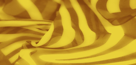 Blurred vibrant yellow fabric with fluid wavy patterns resembling abstract zebra stripes. The folds create a dynamic play of light and shadow for a vivid texture.の写真素材
