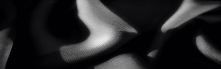 Blur of black fabric with gentle folds and a soft, smooth texture. Subtle highlights create a luxurious, flowing effect, emphasizing the intricate weave pattern.の写真素材