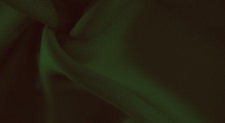 Blurred green fabric with elegant soft folds and shadows, showing its smooth texture and creating a visually pleasing abstract pattern ideal for design backgrounds.の写真素材