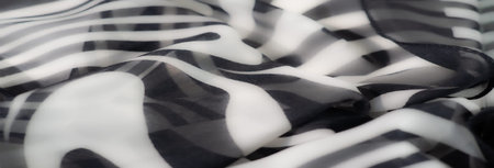 Blur of a close-up black and white fabric displaying elegant swirling patterns. The design is fluid,...