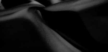 Blur of dark black fabric softly draped with flowing curves. The fine texture reveals smooth shadows...