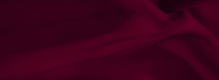 Blurred rich burgundy textile with delicate flowing creases and soft texture. A luxurious abstract fabric background with shadows creating a smooth, refined aesthetic.の写真素材