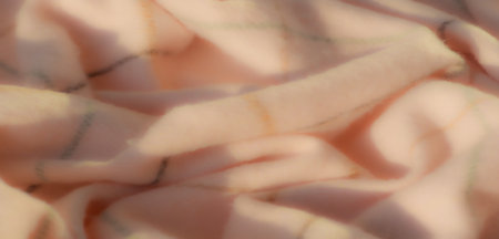 Blurred soft fabric with an elegant plaid pattern featuring pastel pink tones and soft green and black gridlines. The swirling folds create texture and depth.の写真素材